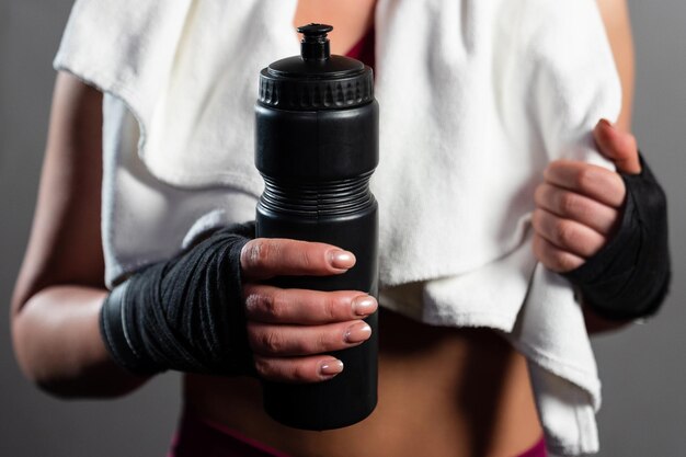 Primer plano de una botella de agua en manos de una mujer después de un entrenamiento