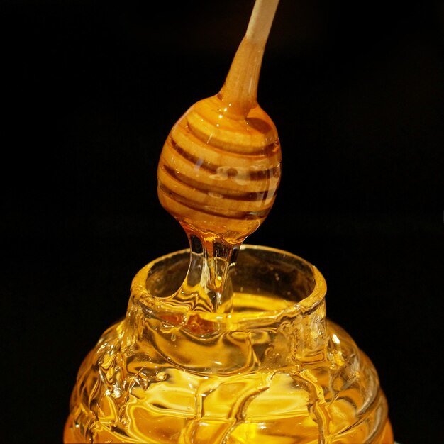 Primer plano de una botella de miel contra un fondo negro