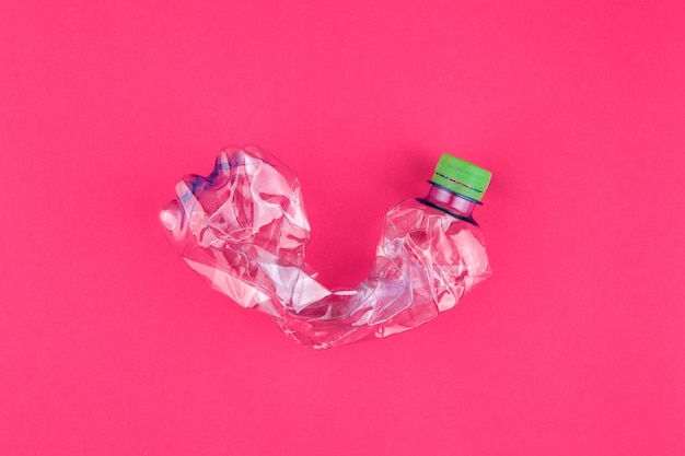 Primer plano de botella de PET triturado sobre fondo rosa vivo