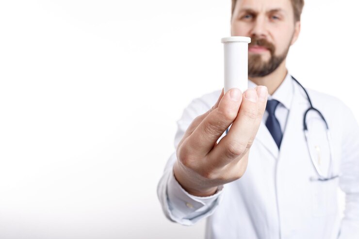 Primer plano de una botella de plástico de drogas sostenida por un médico borroso