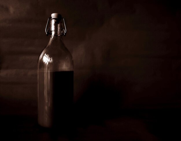 Foto primer plano de una botella vacía en el cuarto oscuro