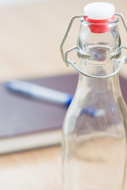 Primer plano de una botella vacía y un libro en la mesa