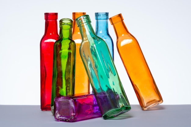 Foto primer plano de botellas de varios colores contra un fondo blanco