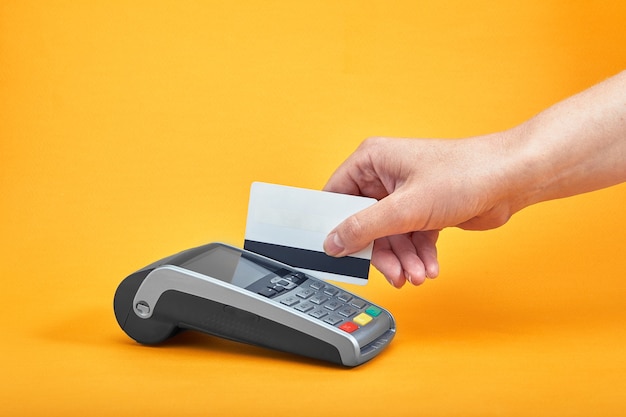 Primer plano de los botones de la máquina de pago con la mano humana sosteniendo la tarjeta de plástico
