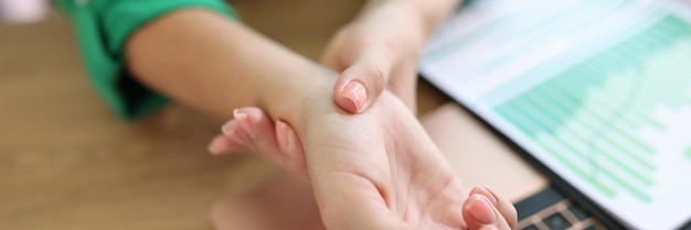 Primer plano de un brazo femenino sosteniendo su muñeca dolorosa causada por un trabajo prolongado en la computadora Síndrome del túnel carpiano y enfermedad de la artritis Mujer empleada sosteniendo la muñeca sintiendo dolor por el síndrome de la oficina