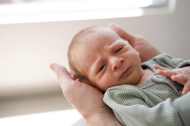 Primer plano de brunet peludo caucásico lindo bebé recién nacido serio en manos masculinas en manos de padre masculino mirando la cámaraCarelovehappiness concepto