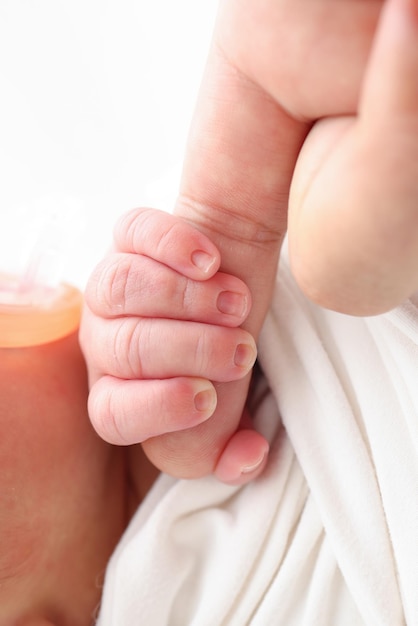 Primer plano de la cabeza de la mano pequeña del bebé, oreja y palma de la madre Foto macro del bebé recién nacido después del nacimiento sosteniendo firmemente el dedo de los padres sobre fondo blanco Concepto de familia y hogar Pediatría sanitaria