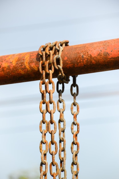 Primer plano de una cadena oxidada colgando contra el cielo