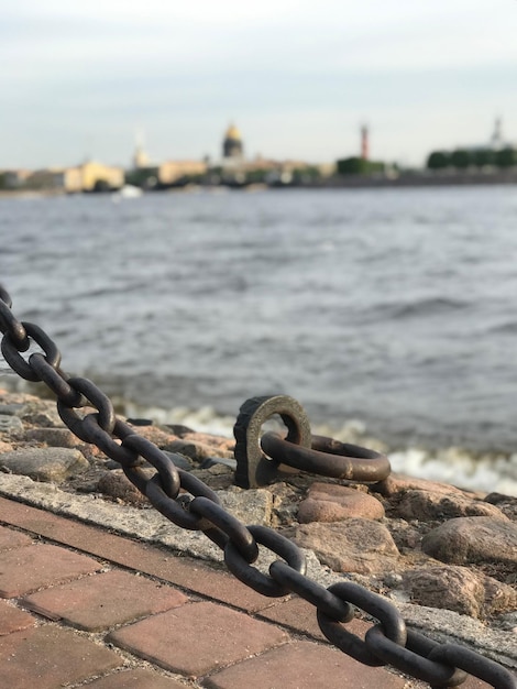 Primer plano de una cadena oxidada en la playa contra el cielo