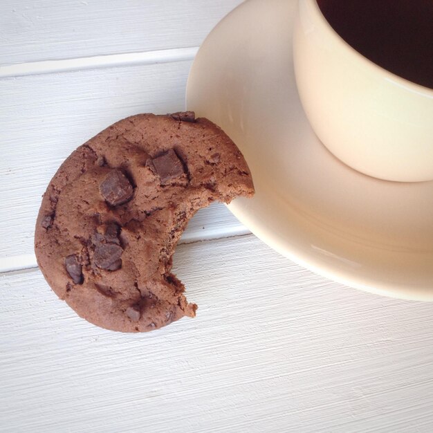 Primer plano de café negro con galletas servidas en la mesa