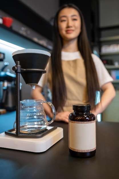 Foto un primer plano de una cafetera de café y una botella de plástico en el mostrador de la barra y un barista pensativo en el fondo