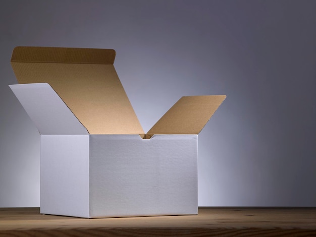 Foto primer plano de una caja de cartón vacía en la mesa contra un fondo gris