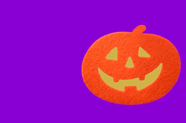 Primer plano calabaza naranja de Halloween sobre fondo violeta con espacio de copia de texto. concepto de Halloween.