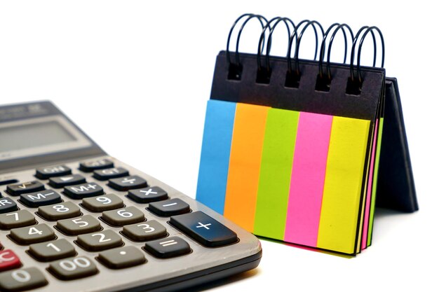 Primer plano de la calculadora y la nota adhesiva contra un fondo blanco