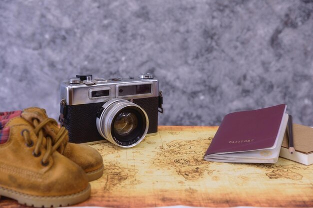 Foto primer plano de la cámara con el pasaporte y los zapatos en la mesa