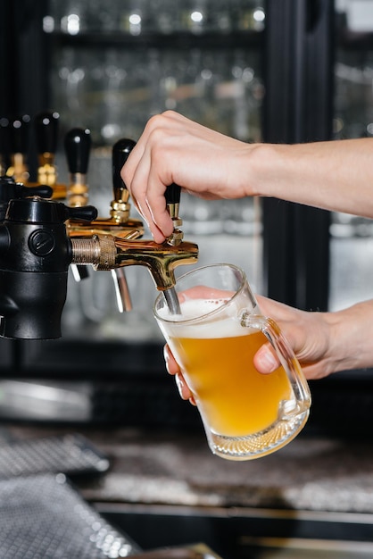 Primer plano del camarero llenando una jarra de cerveza ligera. La barra del bar en el pub.