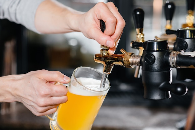 Primer plano del camarero llenando una jarra de cerveza ligera