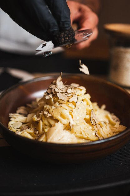 Primer plano del camarero rastrillando trufa negra en la parte superior de la pasta italiana