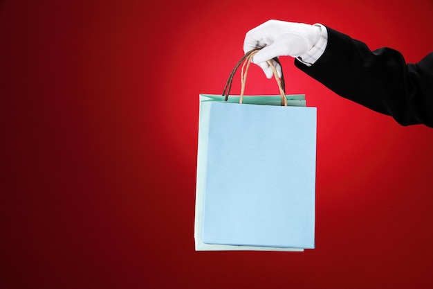 Foto primer plano de un camarero sosteniendo una bolsa de compras contra un fondo rojo