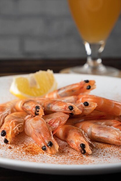 Primer plano de camarones hervidos en un plato y un vaso de cerveza en una mesa de madera