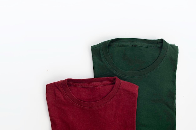 Primer plano de camiseta doblada de color rojo oscuro y verde con fondo blanco