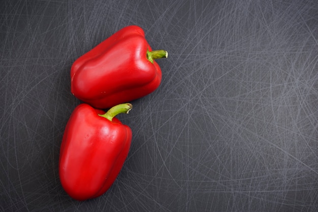 Primer plano de campana roja de fantasía colorida o pimientos dulces sobre fondo negro textura rayada