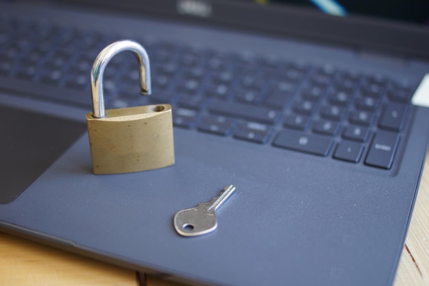 Un primer plano de un candado abierto con una llave en un teclado de portátil