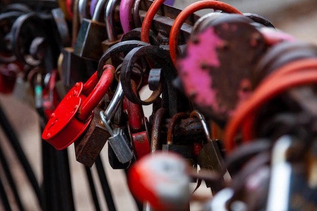 Primer plano de candados de corazones en diferentes colores y formas colgando de la cerca como un signo de amor eterno que se cuelga durante la boda Cultura y costumbres nupciales