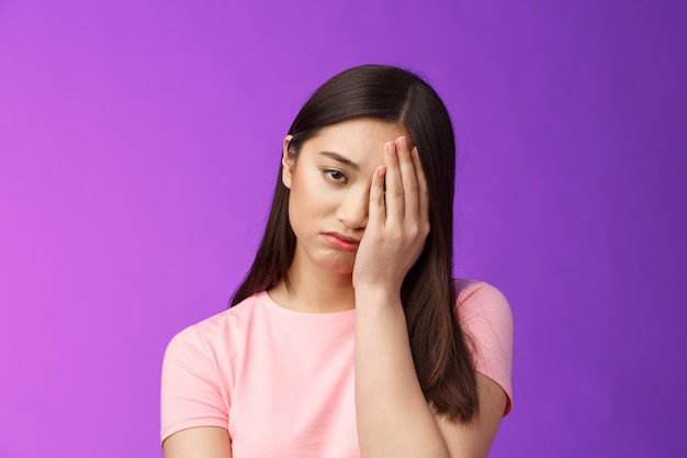 Primer plano cansada niña molesta que se siente perdedora, puñetazo en la cara, hace el signo de facepalm suspirando tristeza, agotado haciendo la tarea difícil, parado infeliz fondo púrpura, arrepentimiento perdido oportunidad. Copia espacio