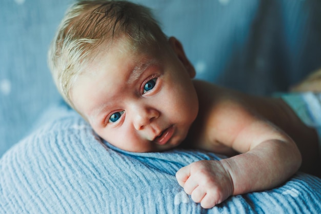 Un primer plano de la cara de un bebé recién nacido. Un recién nacido mira a la cámara. Los ojos abiertos de un bebé recién nacido.