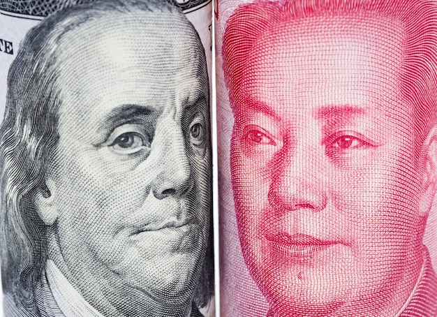 Primer plano cara a cara de Benjamin Franklin y Mao tse tung del billete de dólar estadounidense y el yuan chino.