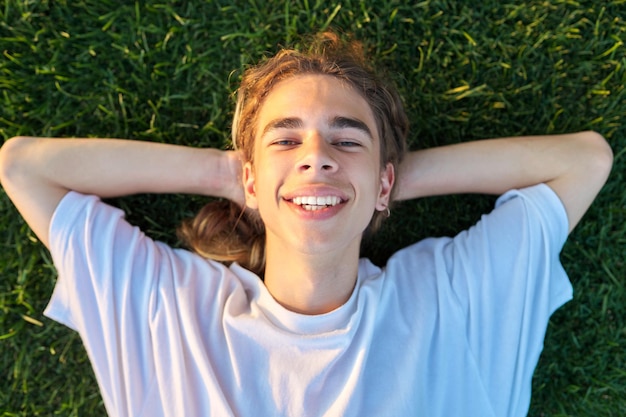 Primer plano de la cara de un chico guapo de 16 a 17 años en la vista superior de la hierba verde