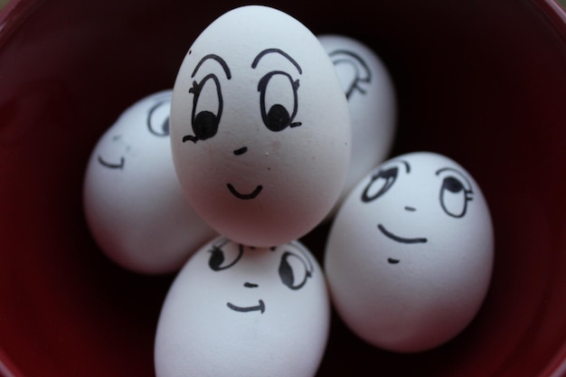 Primer plano de una cara dibujada en huevos de Pascua en un cuenco