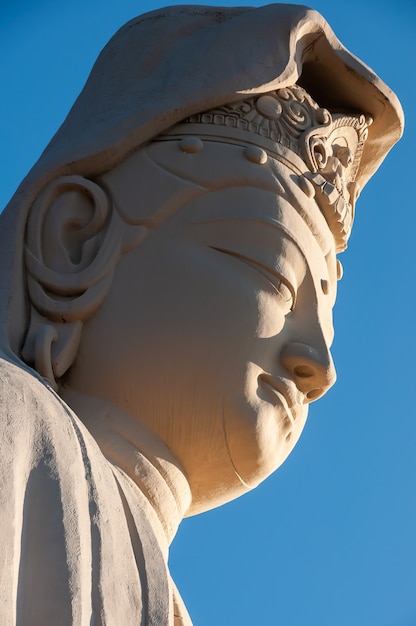 Primer plano de la cara de la estatua de Ryozen Kannon Bodhisattva Avalokitesvara, iluminada por una luz solar increíble.