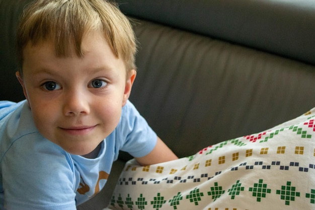 Primer plano de la cara de un hermoso niño de un año acostado en la cama foto de alta calidad