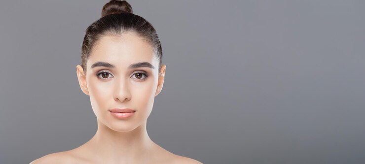Un primer plano de la cara de una mujer con un pan bien hecho en el centro de su cabello sus rasgos son