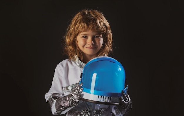 Primer plano de la cara de un pequeño astronauta con casco mirando soñadoramente a un niño pequeño con traje espacial sonriendo a ca