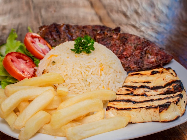 Primer plano de carne asada con ensalada de tomate y papas fritas comida tradicional de carne asada a la barbacoa servida en un plato de mesa de madera con carne asada y ensalada servida sobre fondo de madera