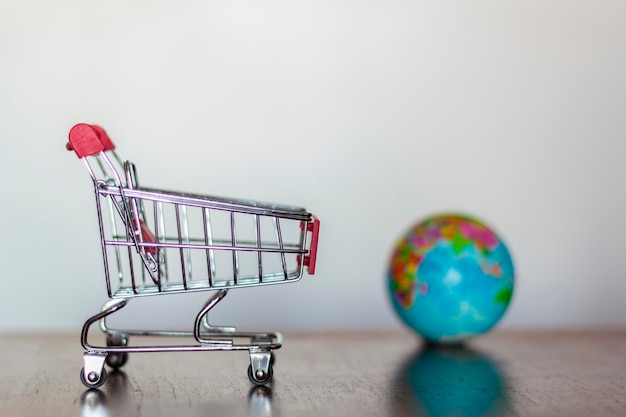 Primer plano del carrito de compras y el globo sobre la mesa contra la pared