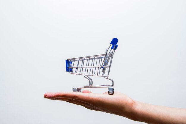 Primer plano del carrito de compras con la mano contra un fondo blanco