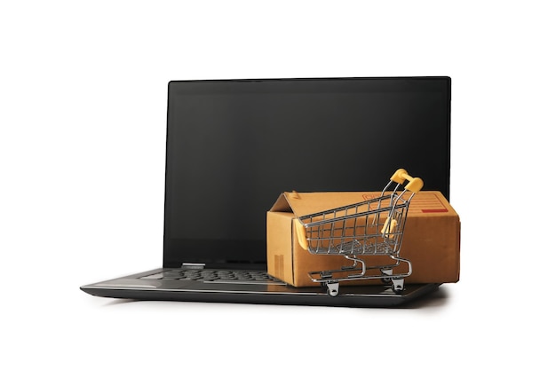 Primer plano del carrito de compras y el paquete en la computadora portátil contra un fondo blanco