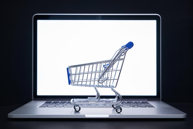 Primer plano del carrito de compras en el portátil contra un fondo negro
