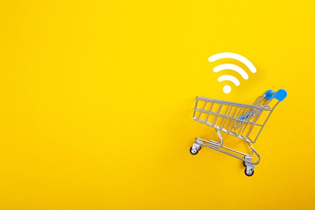 Primer plano de un carrito de compras con señal wifi sobre fondo amarillo