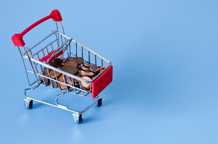 Foto primer plano del carro de supermercado para ir de compras, una moneda en una cesta, monedas. fondo azul.