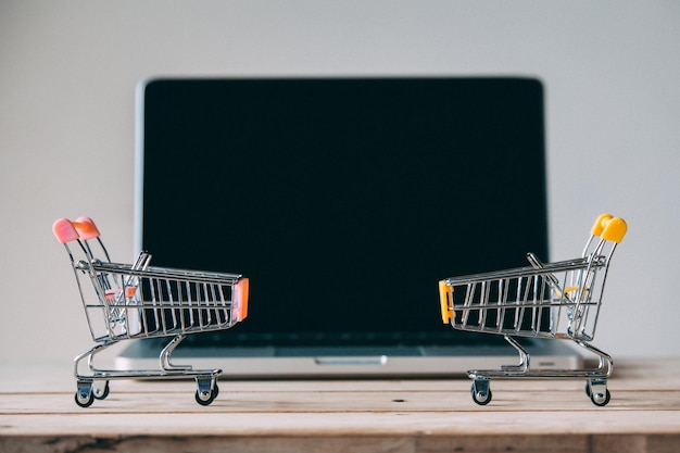 Primer plano de los carros de compras y la computadora portátil en la mesa