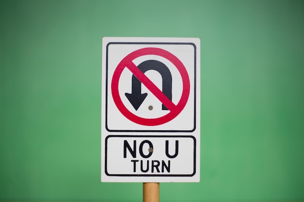 Primer plano de un cartel de juguete "NO U TURN" contra un fondo verde