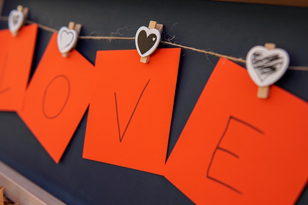 Primer plano de un cartón rojo con la palabra amor colgando de corazones en un marco de fotos amor en el día de san valentín