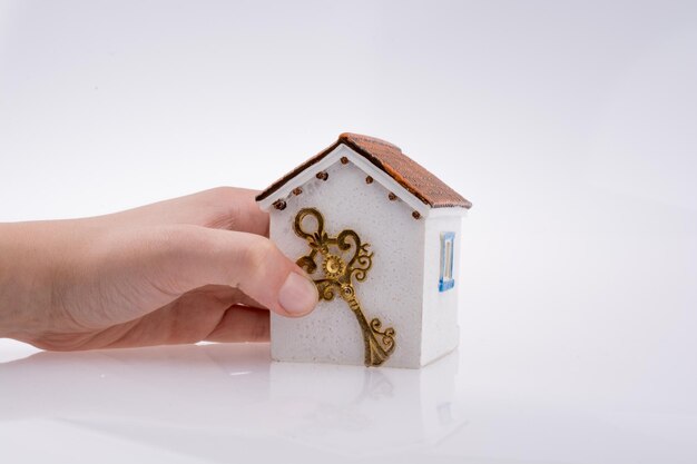 Foto primer plano de una casa modelo con la mano sobre un fondo blanco