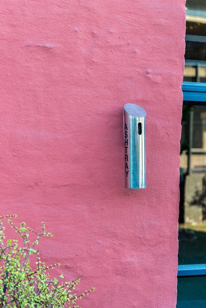 Foto primer plano de un cenicero de metal en la pared rosada