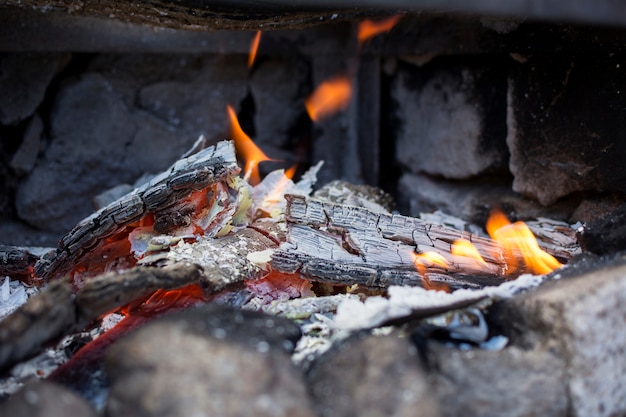 Primer plano de las cenizas y las llamas de una parrilla.